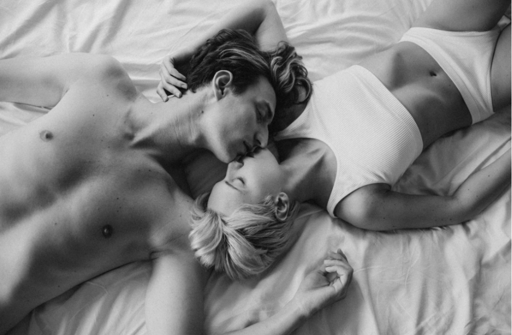 Grayscale-photo-of-a-romantic-couple-kissing-on-the-bed